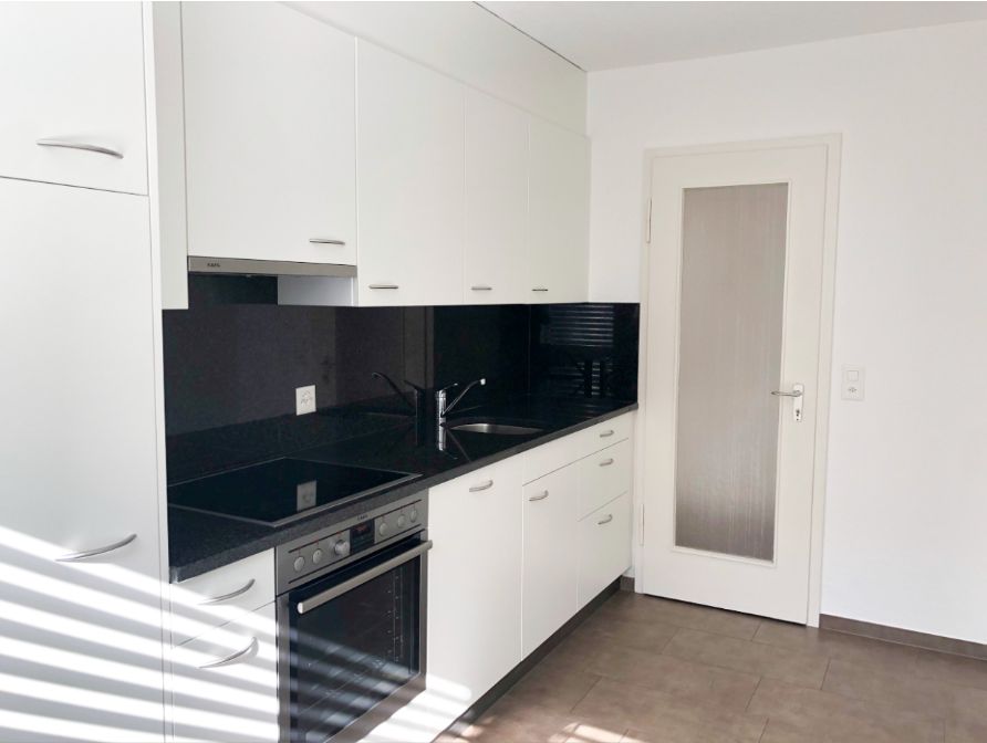 Moderne Küche mit weißen Fronten und schwarzer Arbeitsfläche