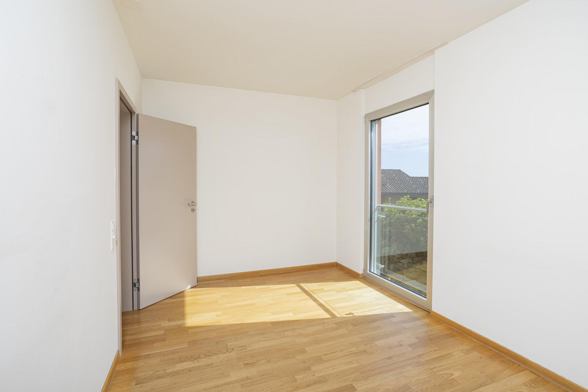 Heller leerer Raum mit Holzboden und Balkontür