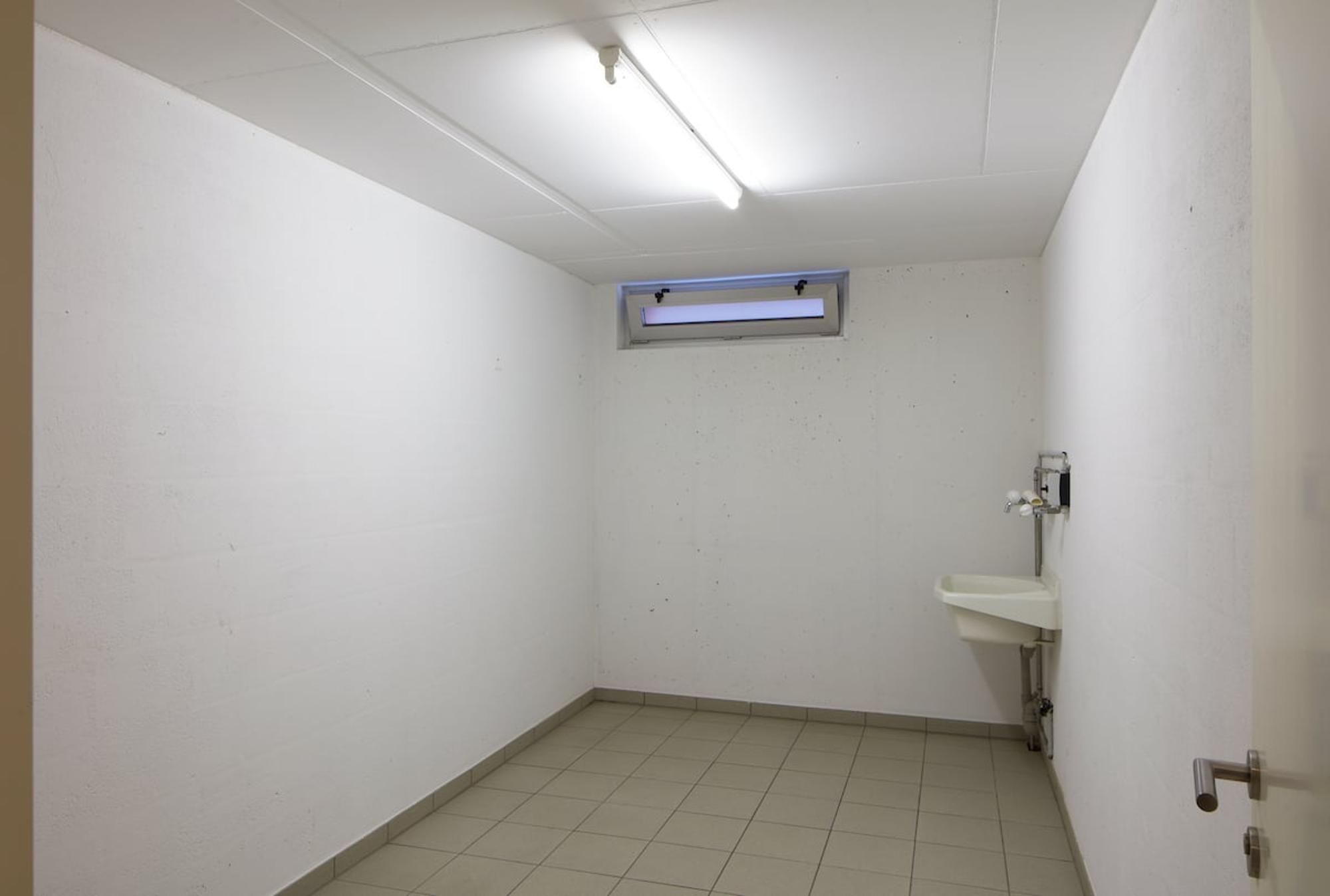 Kleiner Nutzraum mit Bodenfliesen und Wandwaschbecken
