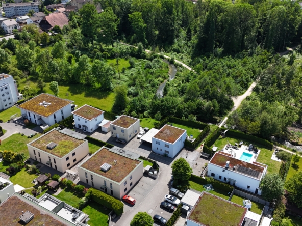 Luftaufnahme eines Wohngebiets am Waldrand mit Pool