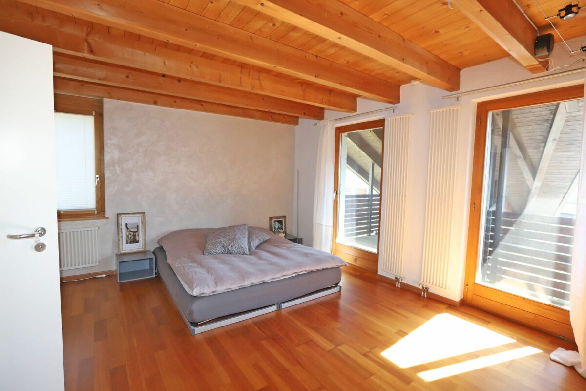 Schlafzimmer mit Holzbalkendecke und großen Fenstern