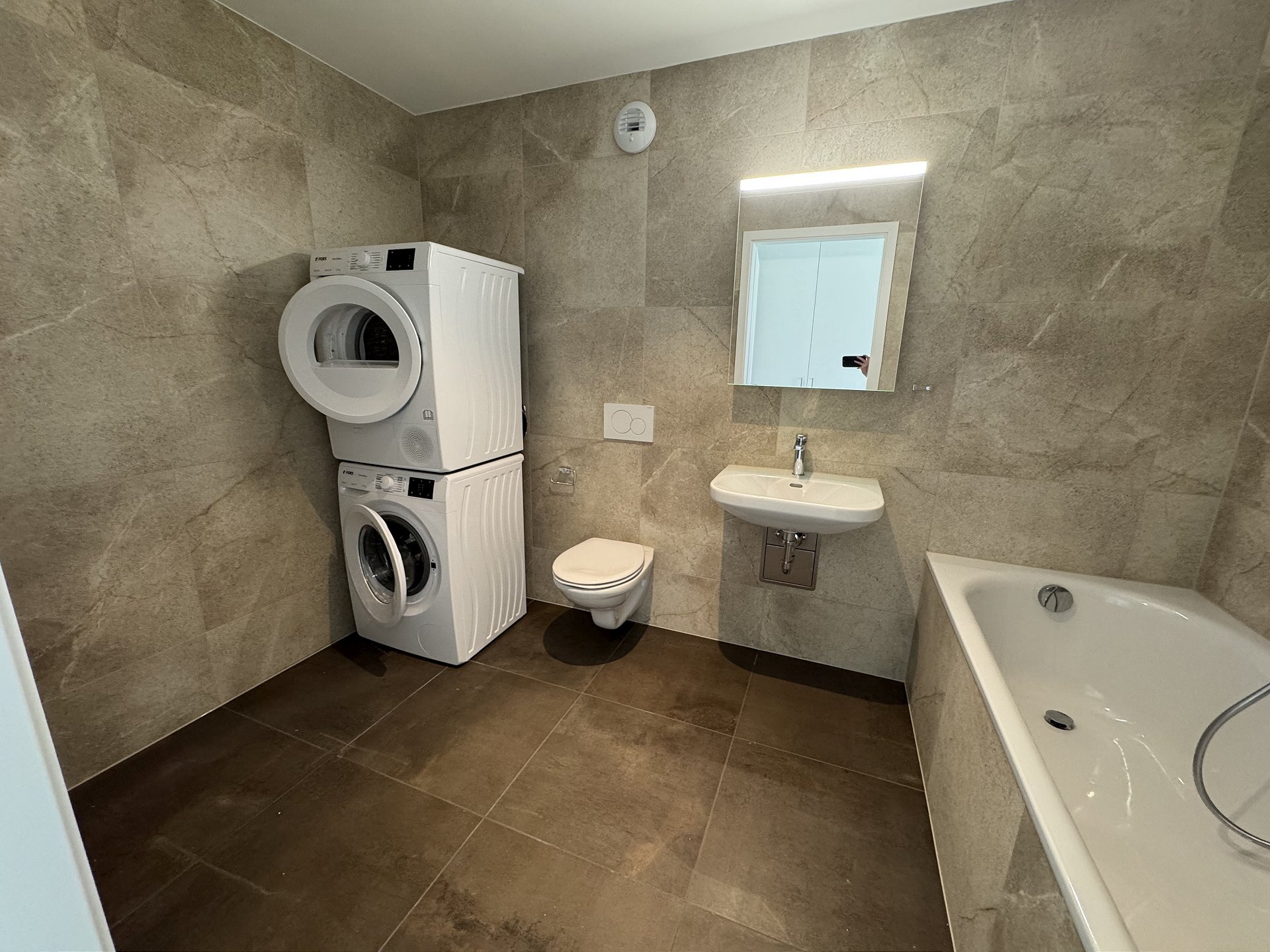 Modernes Bad mit Waschtrockner und Wanne