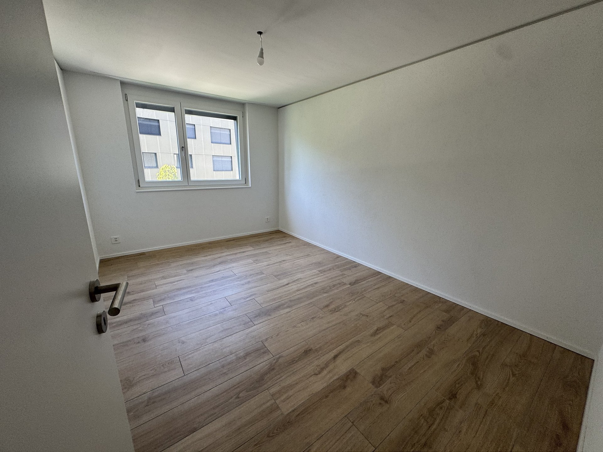 Leeres Schlafzimmer mit Holzoptikboden und Fenster