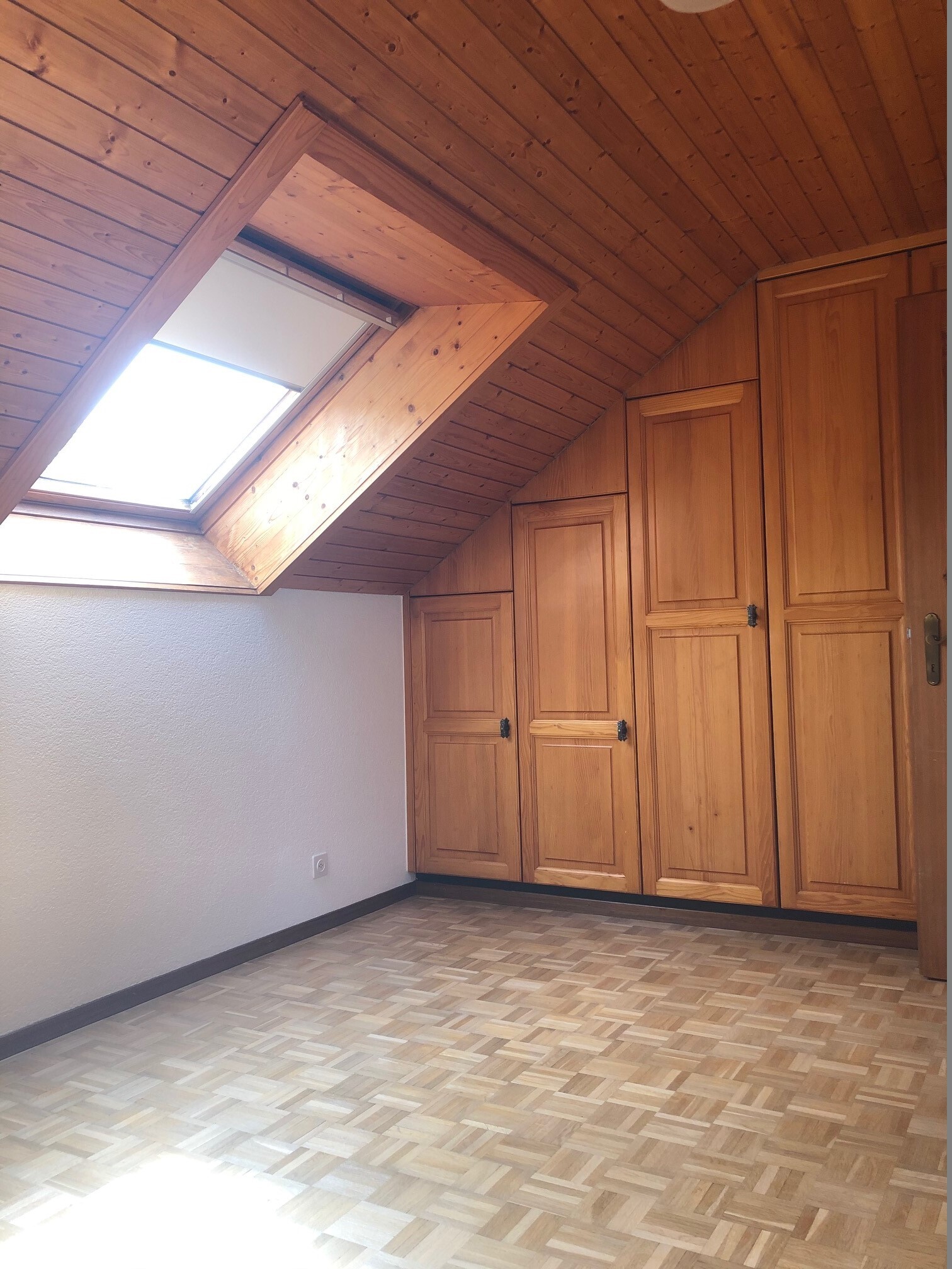 Dachzimmer mit Holzverkleidung und Einbauschränken