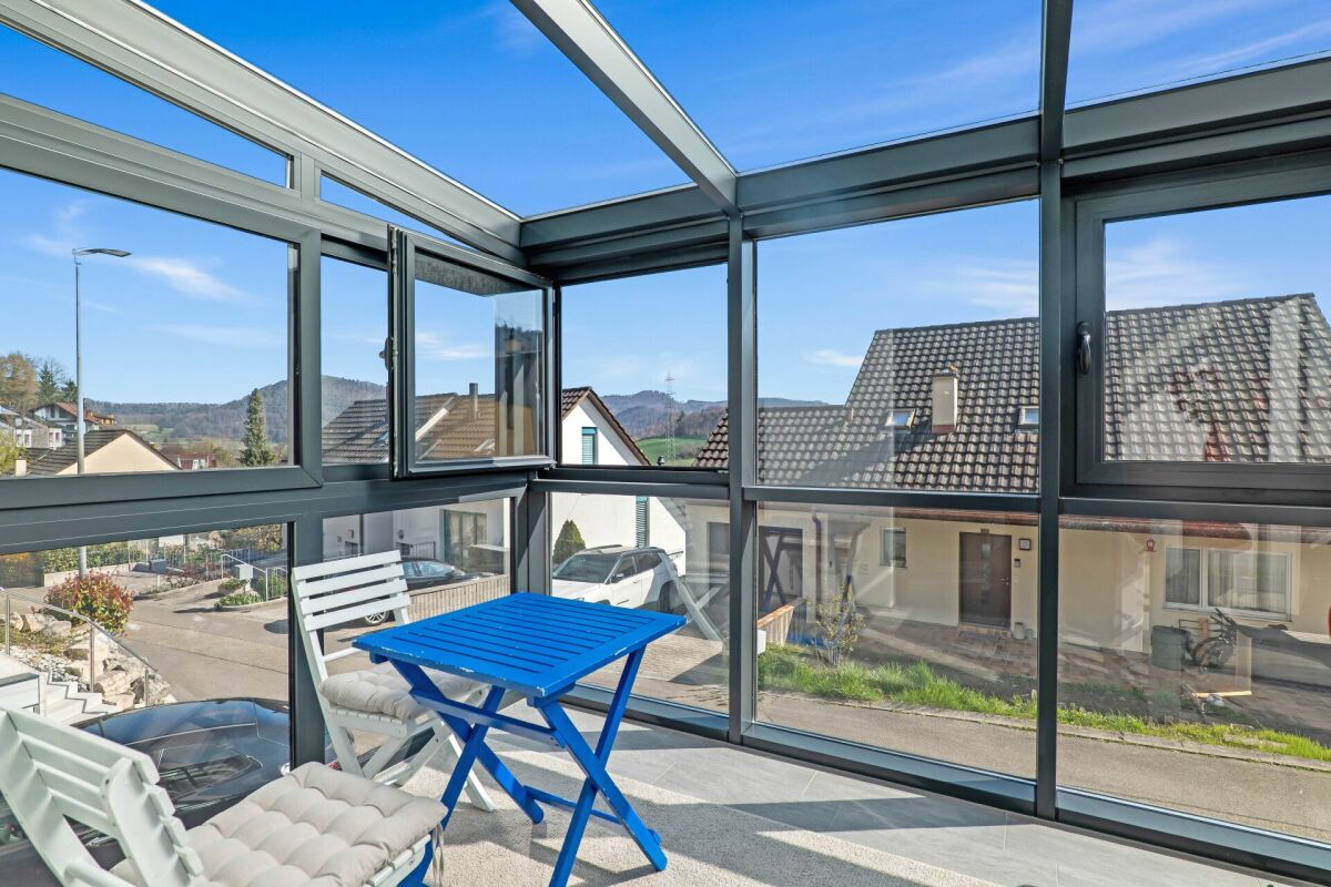 Verglaster Balkon mit Sitzgruppe und Bergblick