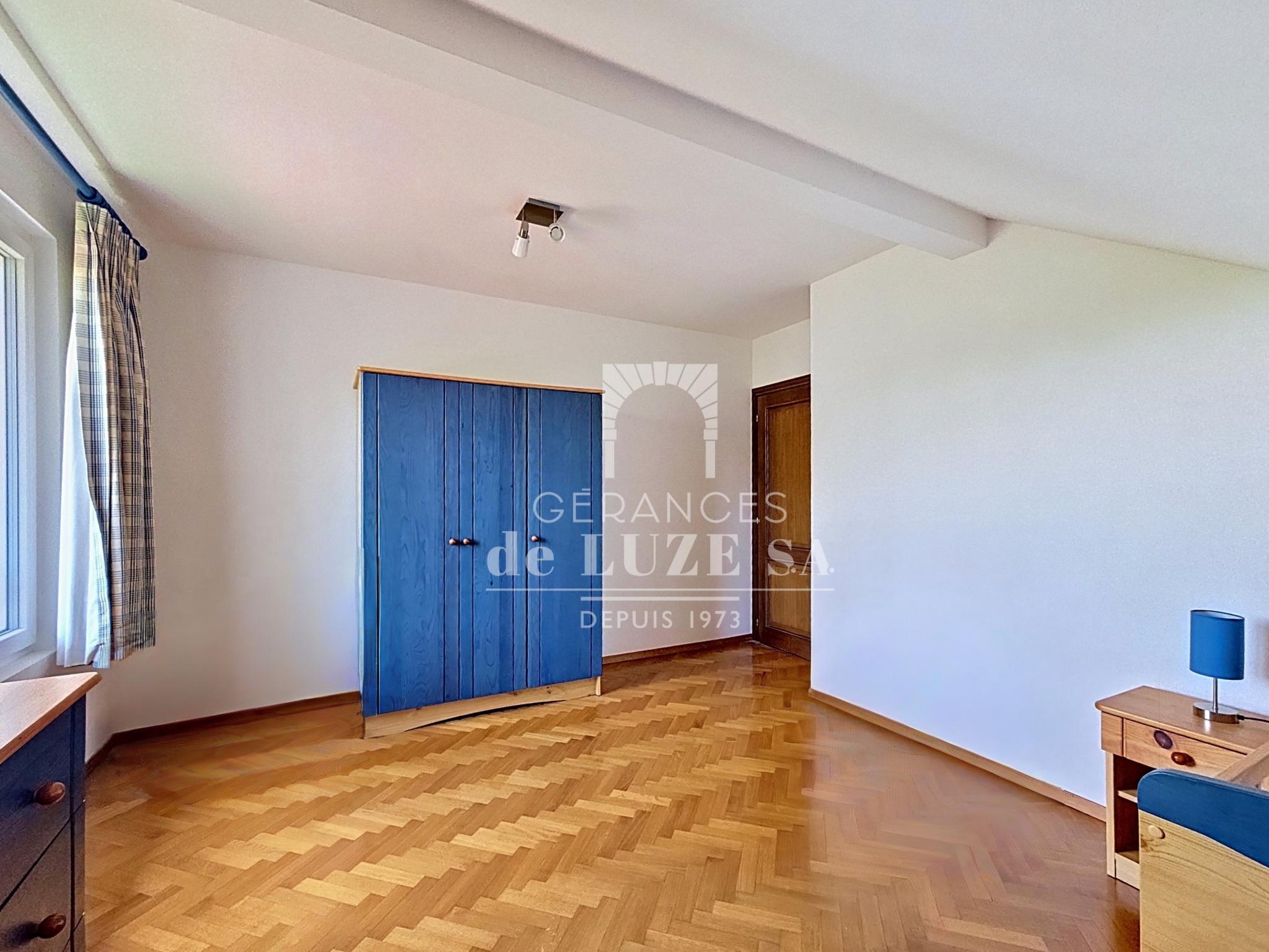 Helles Schlafzimmer mit Parkettboden und blauem Kleiderschrank