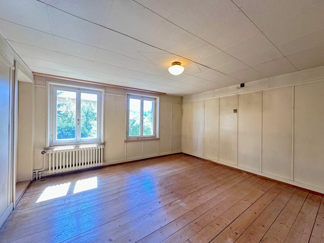 Heller leerer Raum mit Holzfußboden und zwei Fenstern