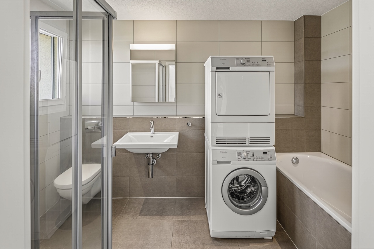 Modernes Badezimmer mit Dusche, Wanne und Waschmaschinen-Turm