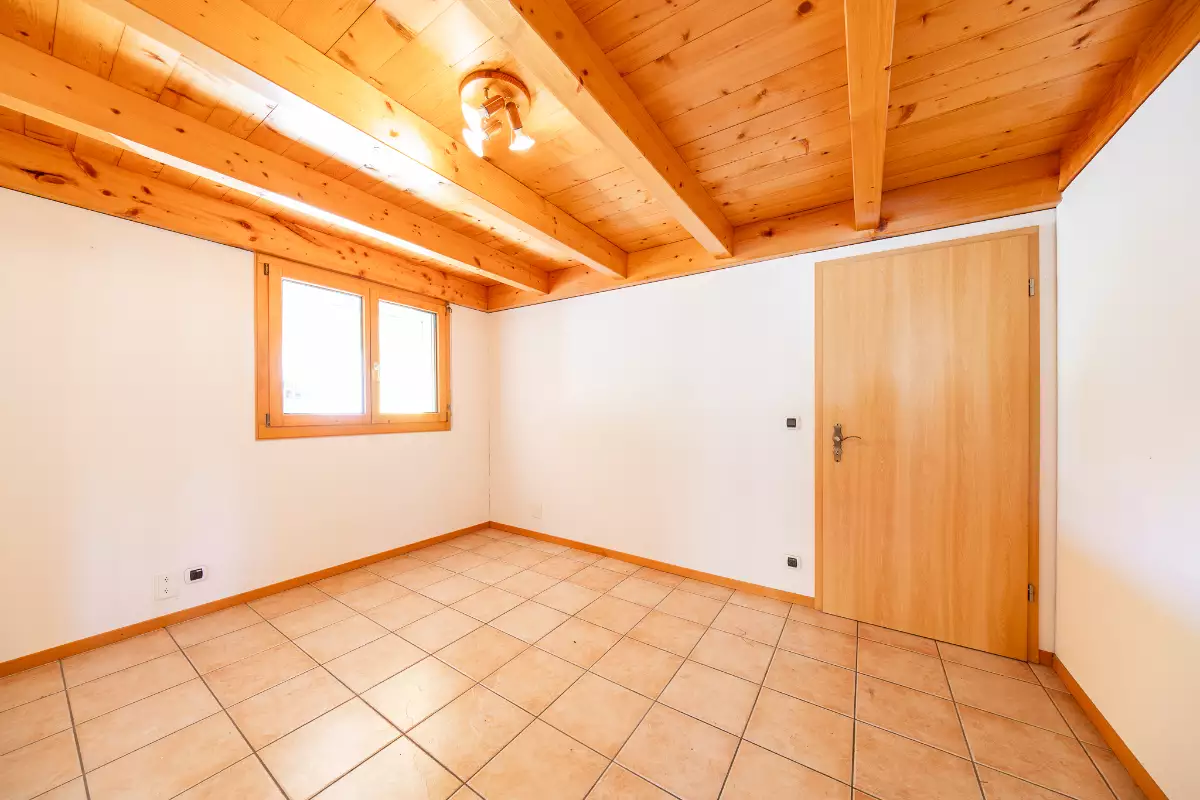Heller leerer Raum mit Holzbalkendecke und Fliesenboden