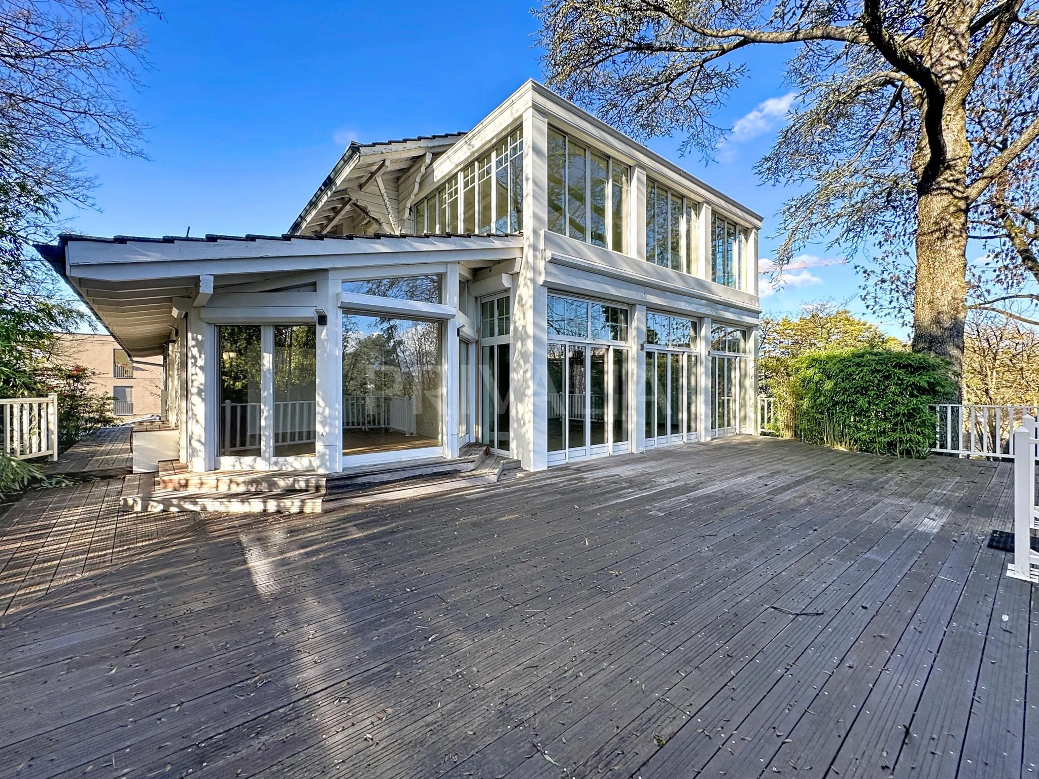 Große moderne Holzterrasse mit verglastem Haus
