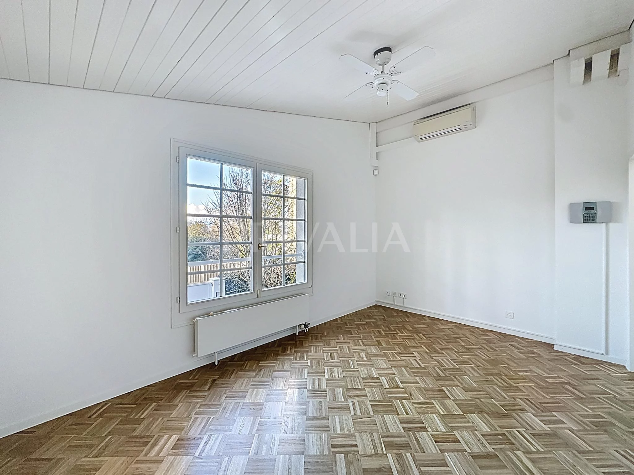 Helles, leerstehendes Zimmer mit Parkettboden und Fenster