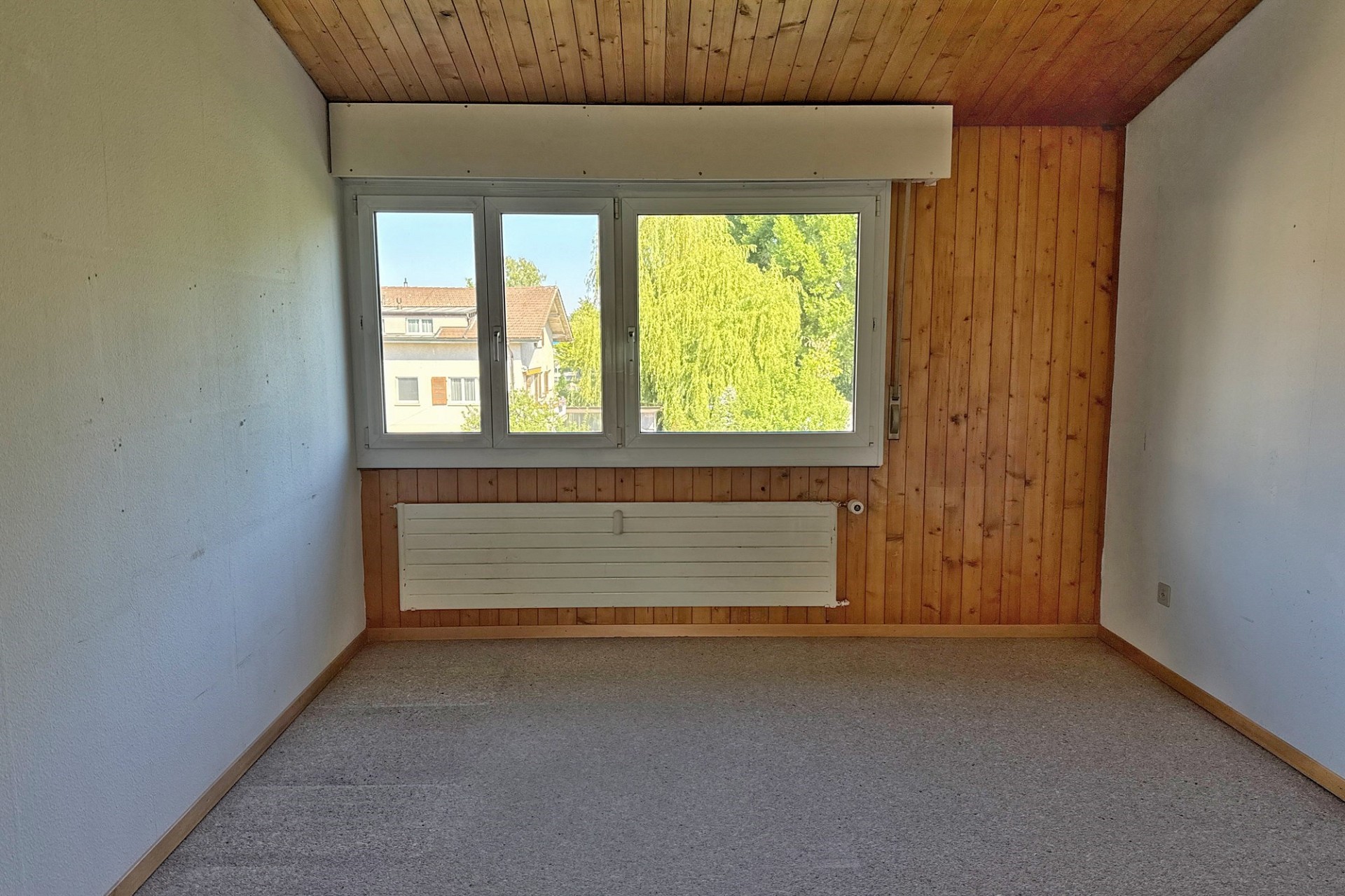 Leerer Raum mit Holzdecke und großem Fenster