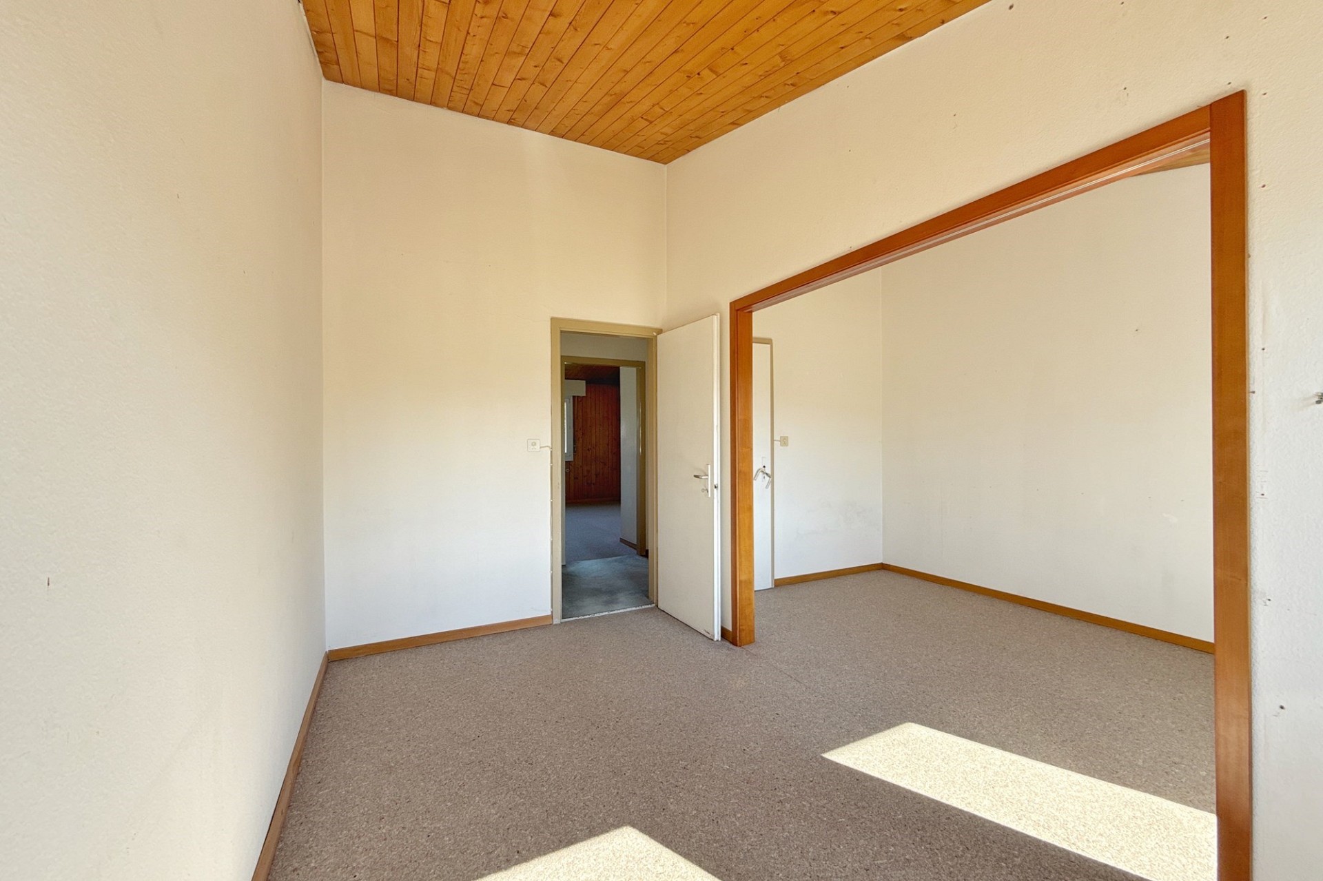 Leerer Raum mit Holzdecke und Teppichboden