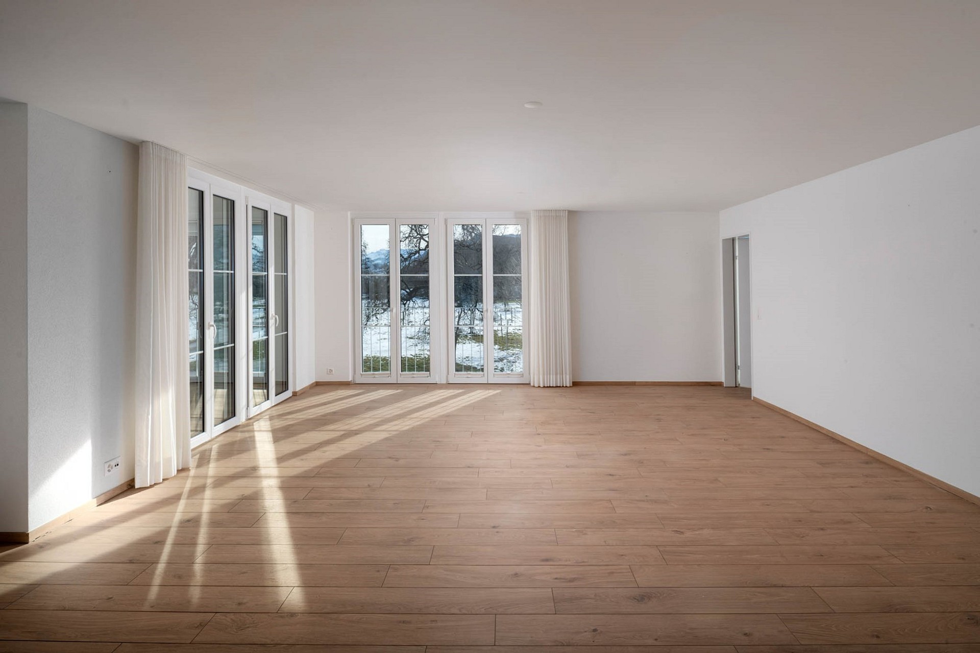 Heller leerer Wohnraum mit großen Fenstern