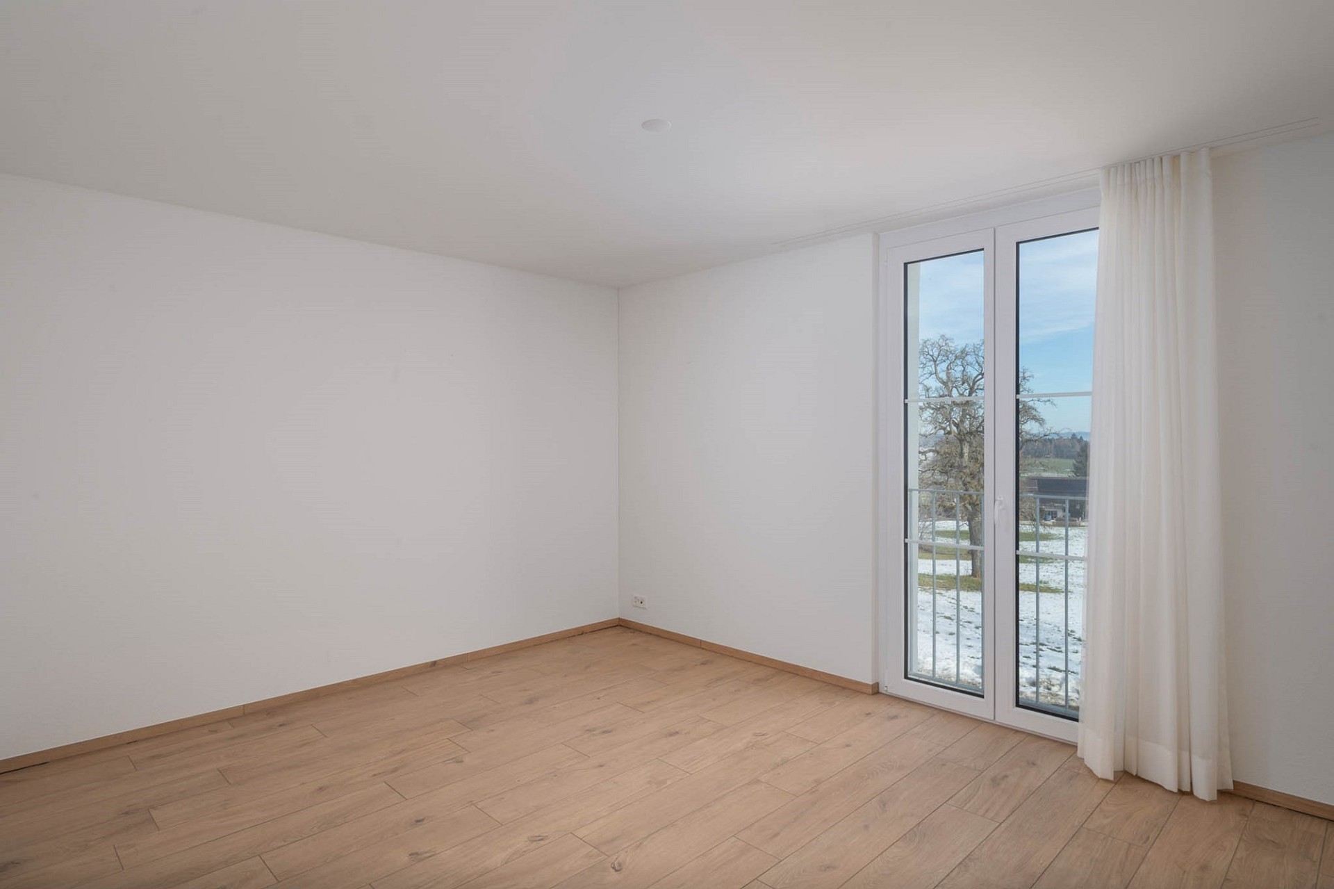 Leeres, helles Zimmer mit Balkon- bzw. Terrassentür