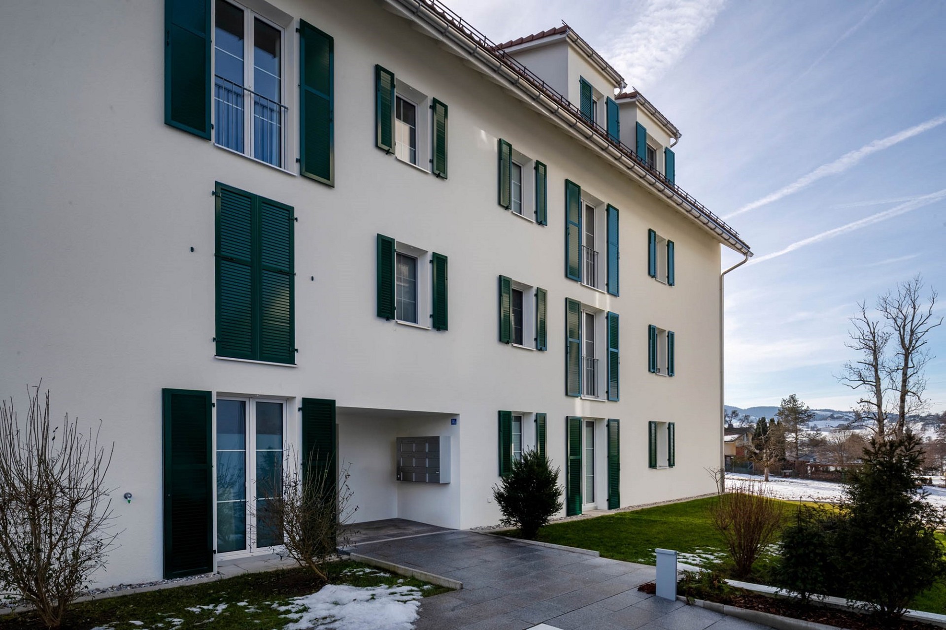 Mehrfamilienhaus mit grünen Fensterläden