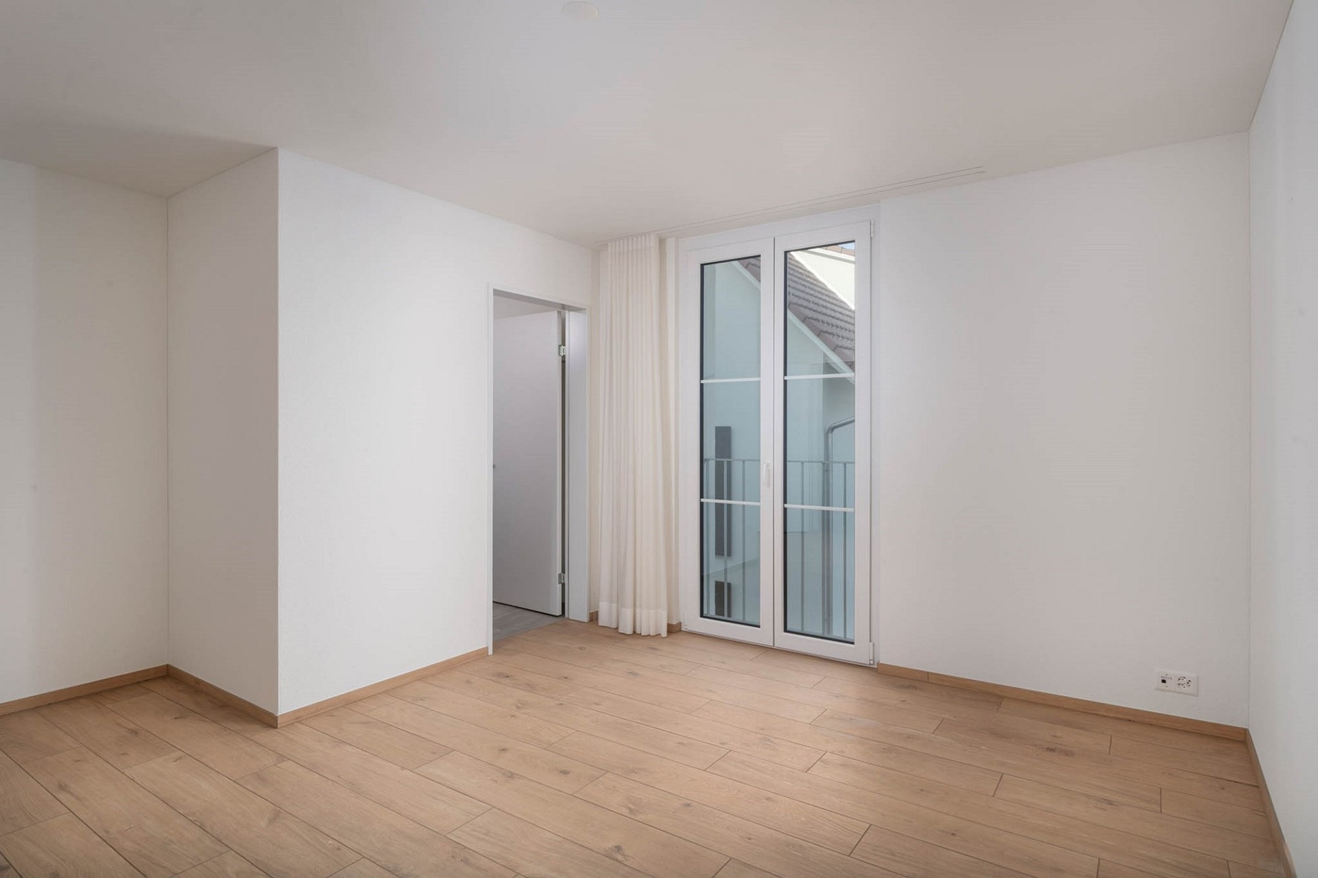 Helles, leeres Zimmer mit Balkon- bzw. Terrassentür