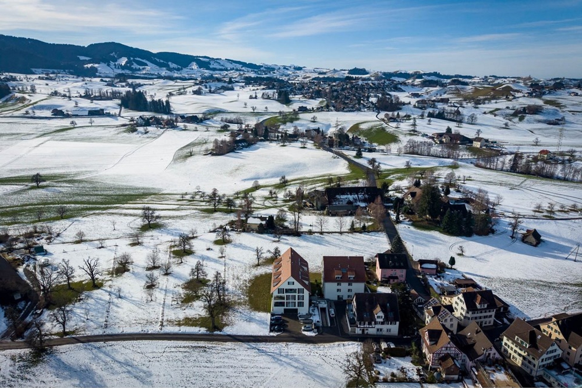 Luftaufnahme einer verschneiten ländlichen Landschaft mit Siedlung
