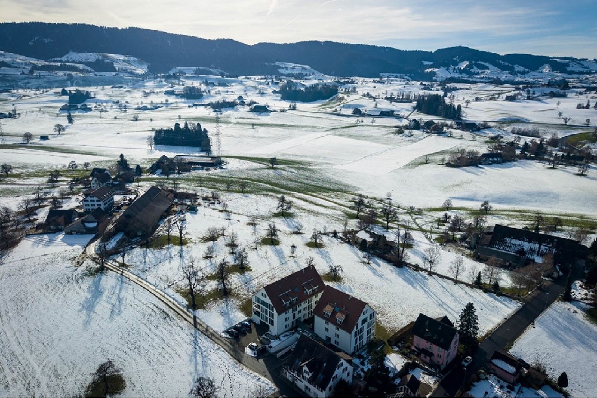 Luftaufnahme einer verschneiten ländlichen Landschaft mit verstreuten Gebäuden