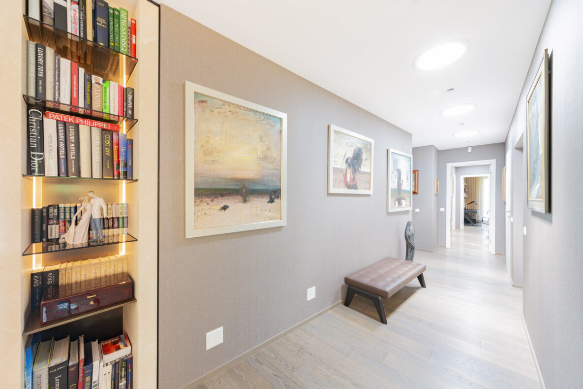 Heller Flur mit Kunst und beleuchteter Bücherregal-Nische