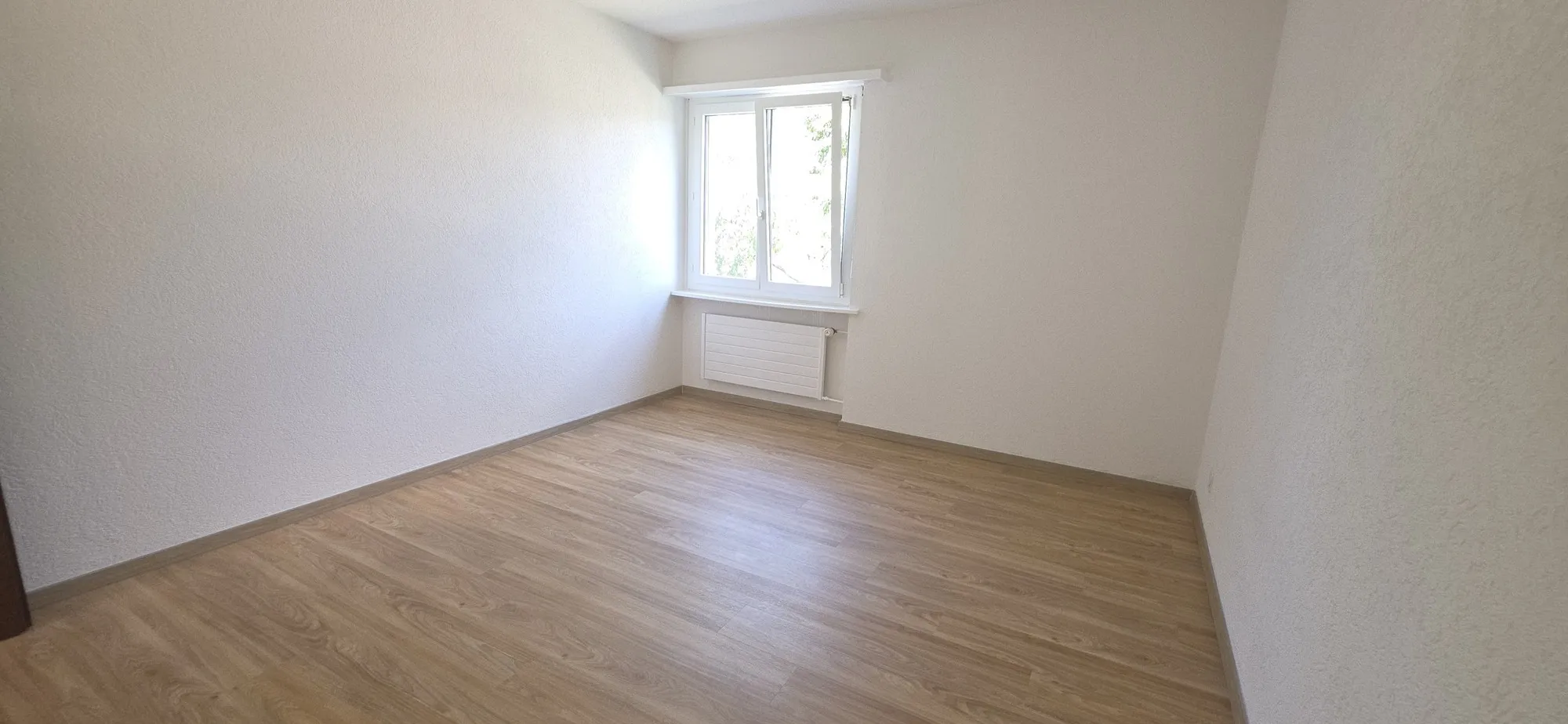 Helles, leeres Zimmer mit Fenster