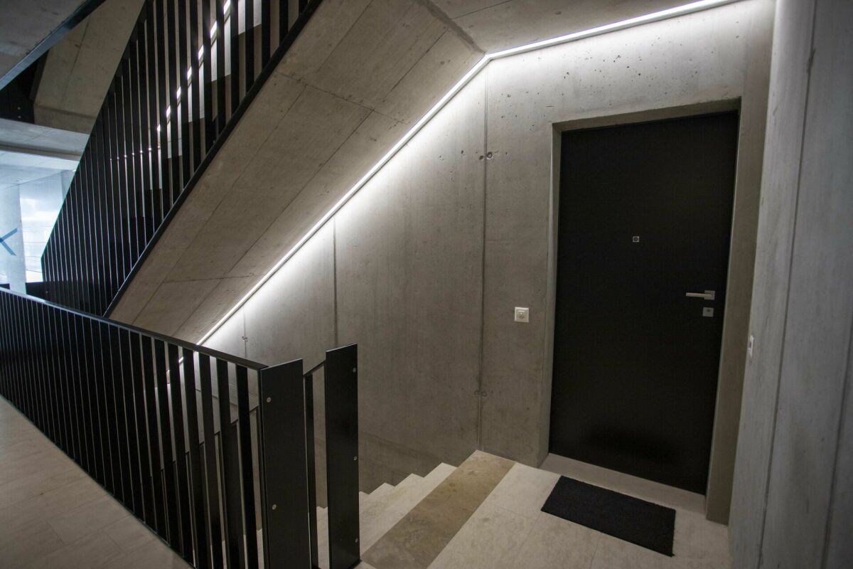 Treppenhaus mit Betonwänden und dunkler Tür