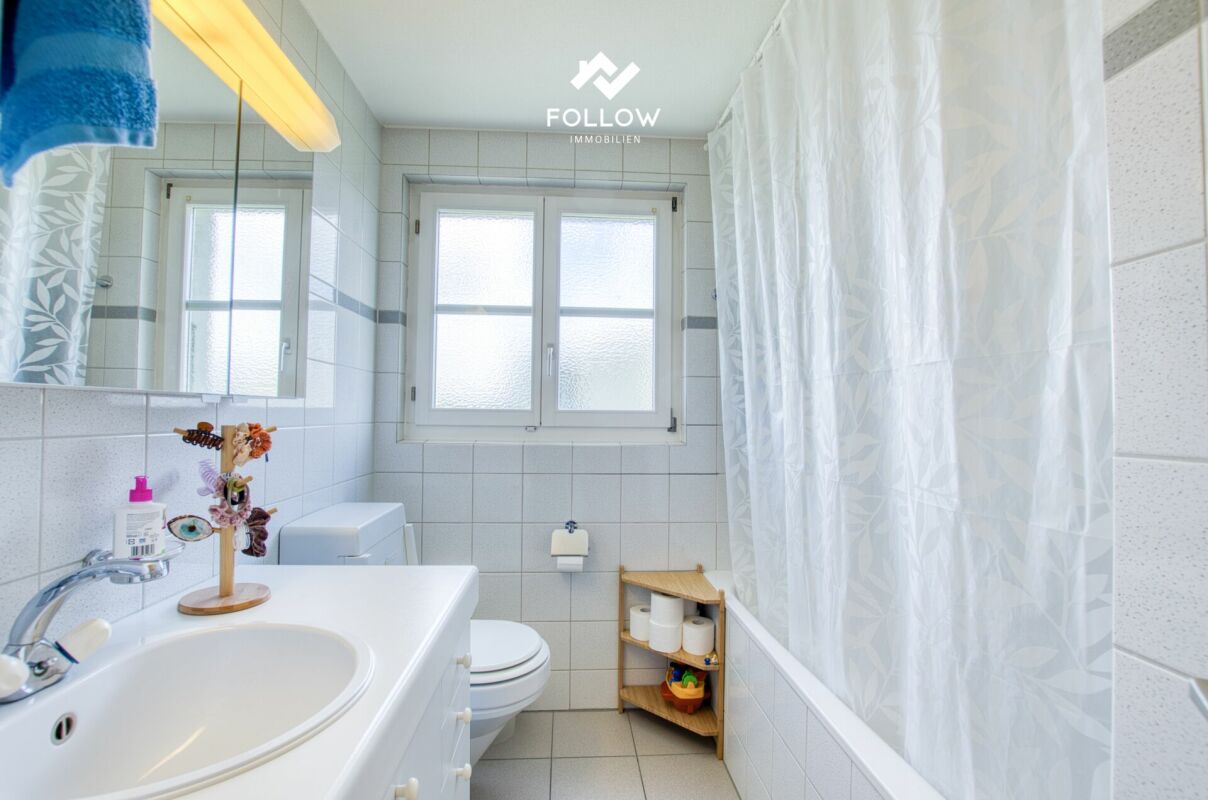 Helles Badezimmer mit Fenster und Badewanne