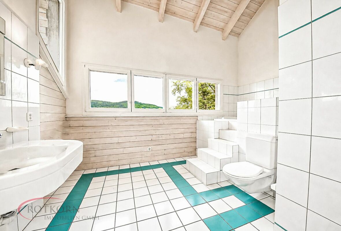 Helles Badezimmer mit Holzdecke und grünem Bodenakzent