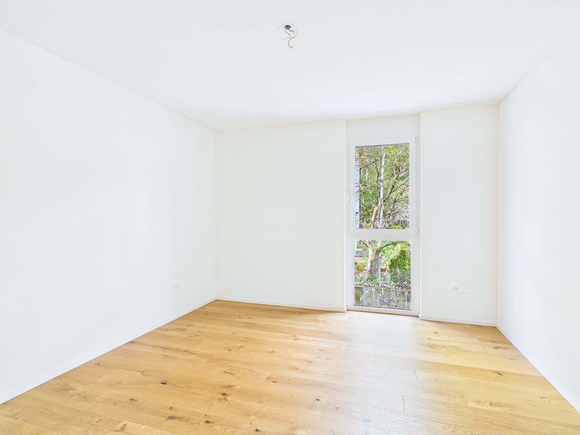 Heller leerer Raum mit Holzfußboden und schmalem Fenster