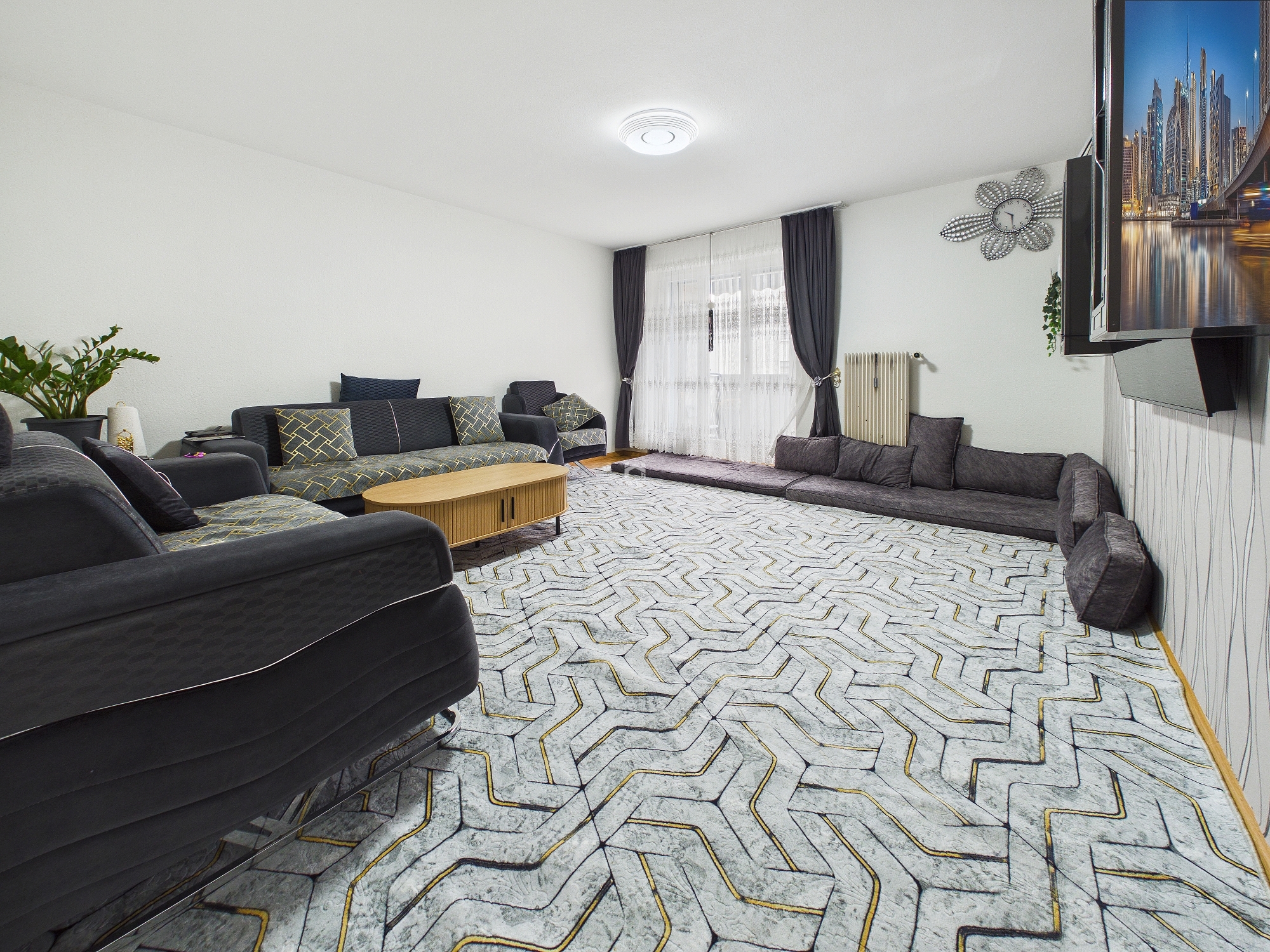 Großes Wohnzimmer mit dunklen Sofas und gemustertem Teppich