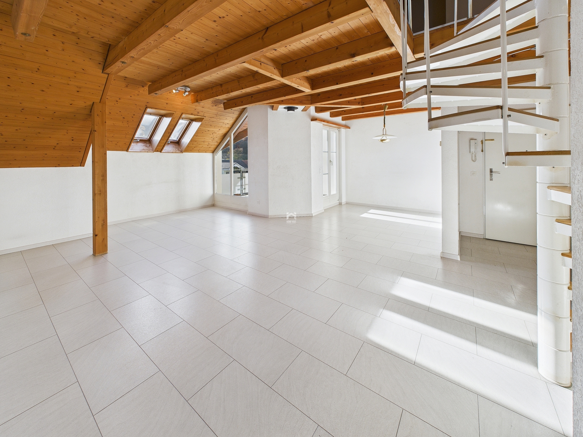 Heller Dachgeschossraum mit sichtbarer Holzdecke und Wendeltreppe