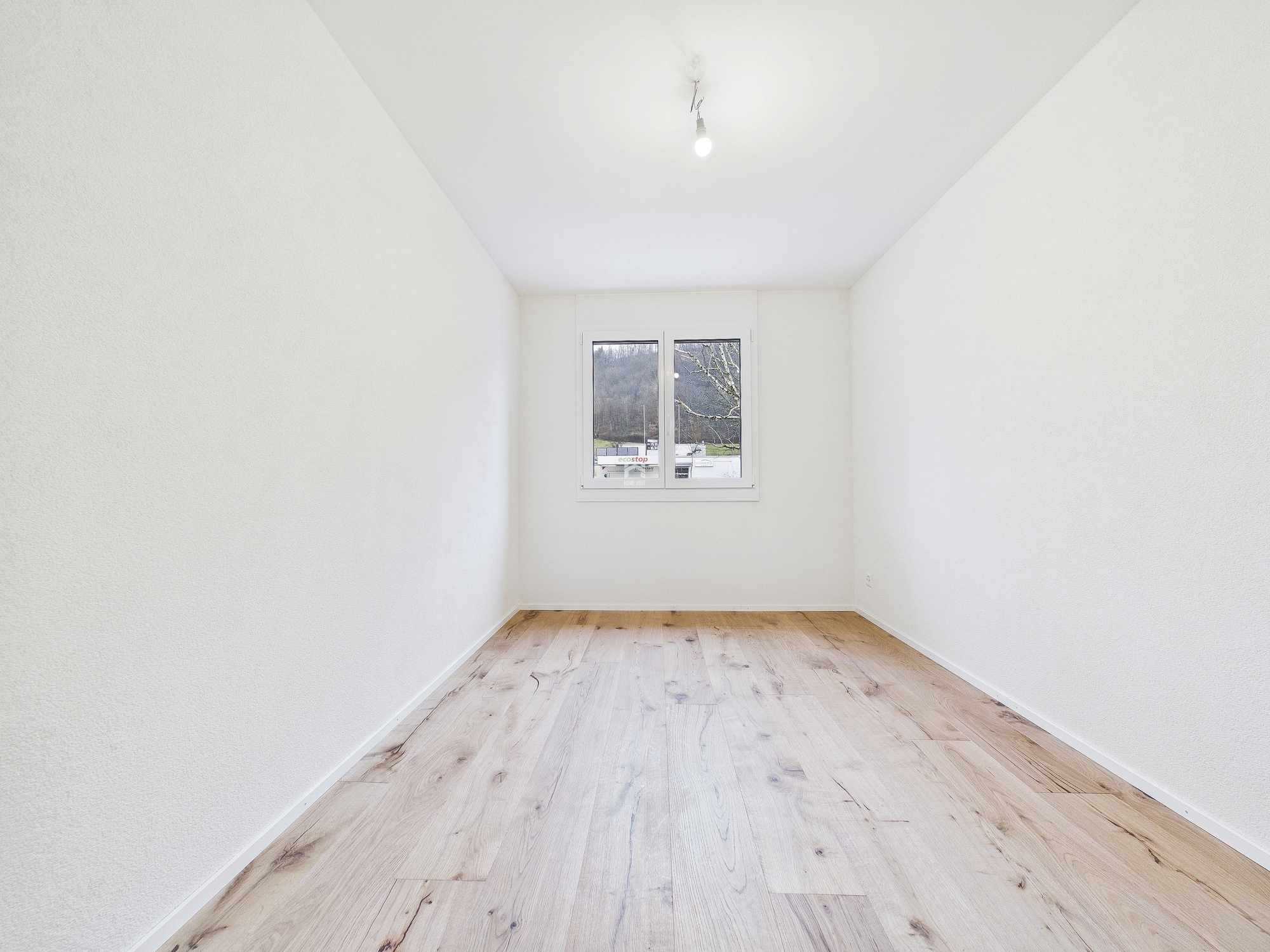Leerer, heller Raum mit Holzfußboden und Fenster