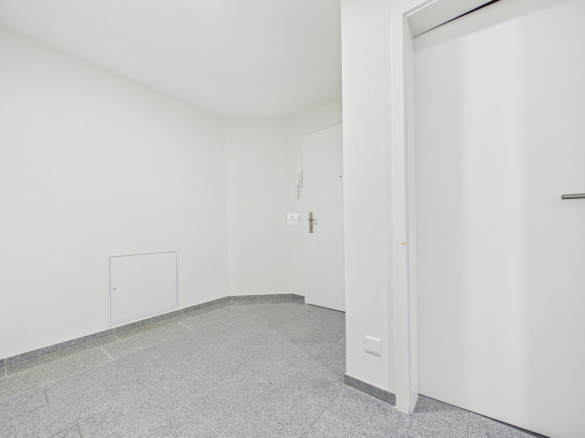 Heller Eingangsbereich mit Fliesenboden und weißen Türen