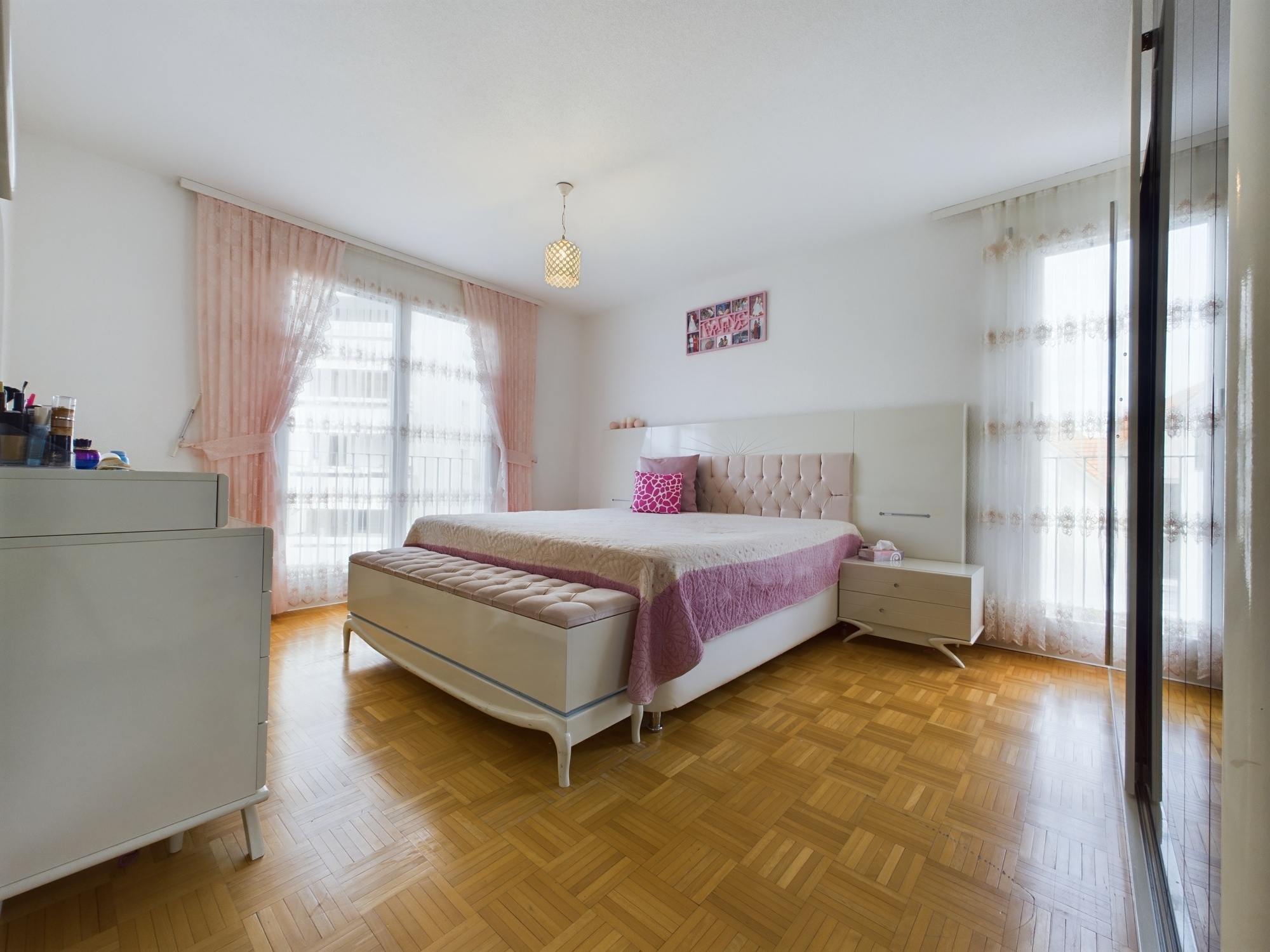 Helles Schlafzimmer mit Doppelbett und pastellfarbener Einrichtung