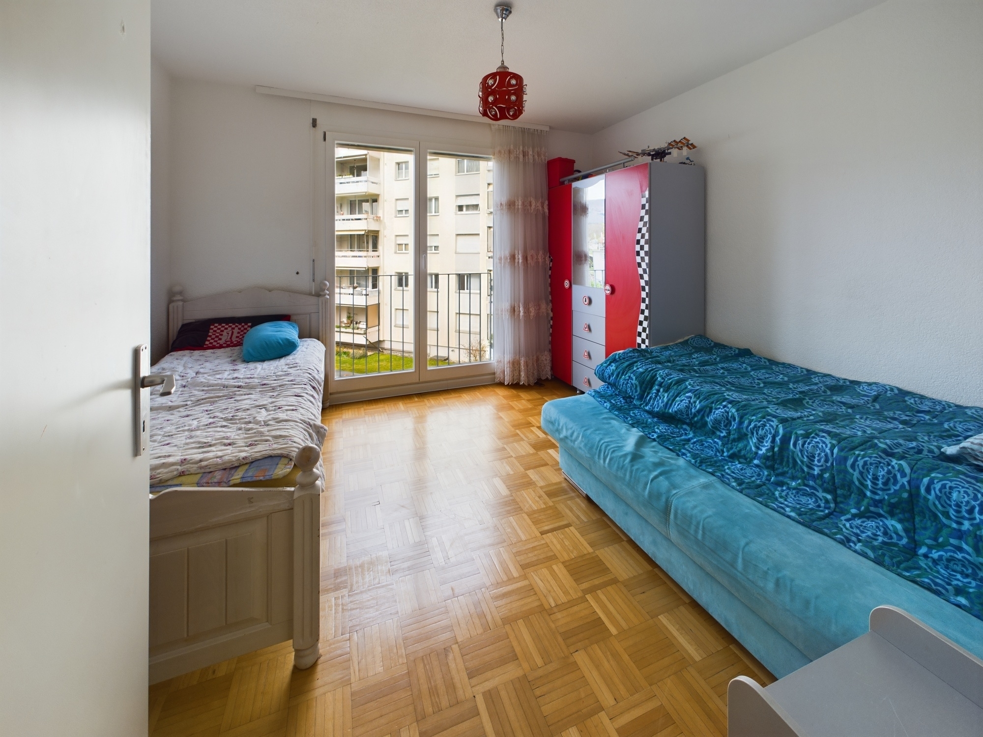 Kinderzimmer mit zwei Einzelbetten und Balkonblick