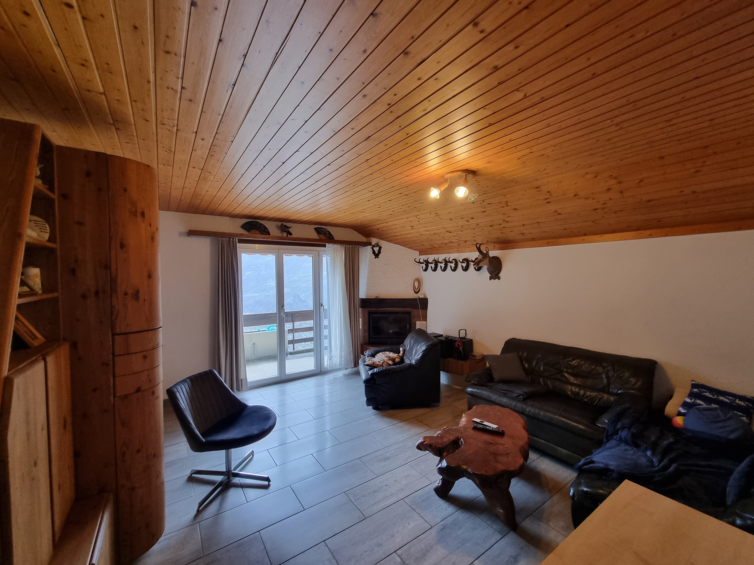 Gemütliches Wohn-/Sitzzimmer mit Holzdecke und Balkonblick