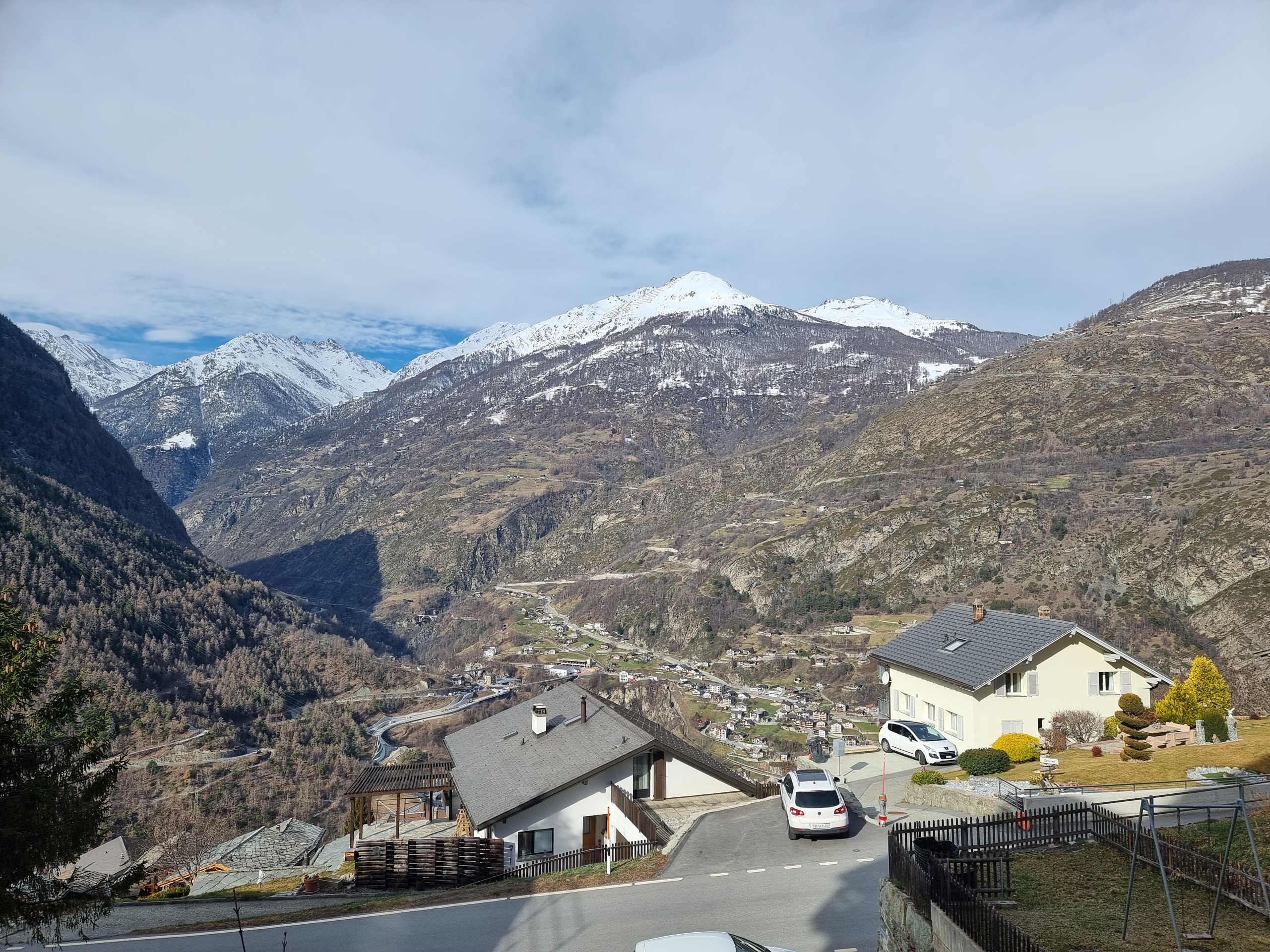 Bergtal mit Wohnhäusern und Schneegipfeln