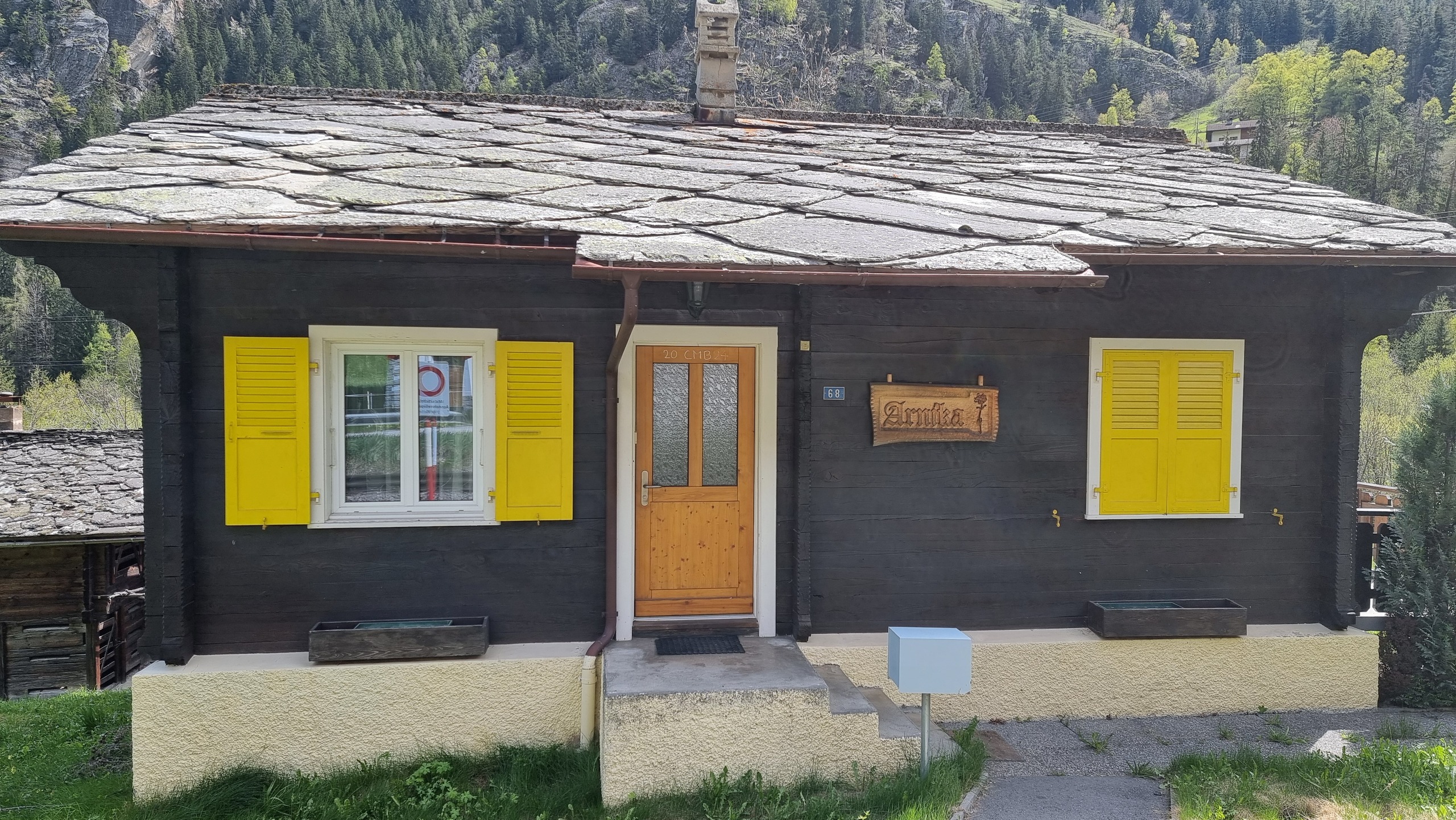 Alpenhaus mit Schieferdach und gelben Fensterläden