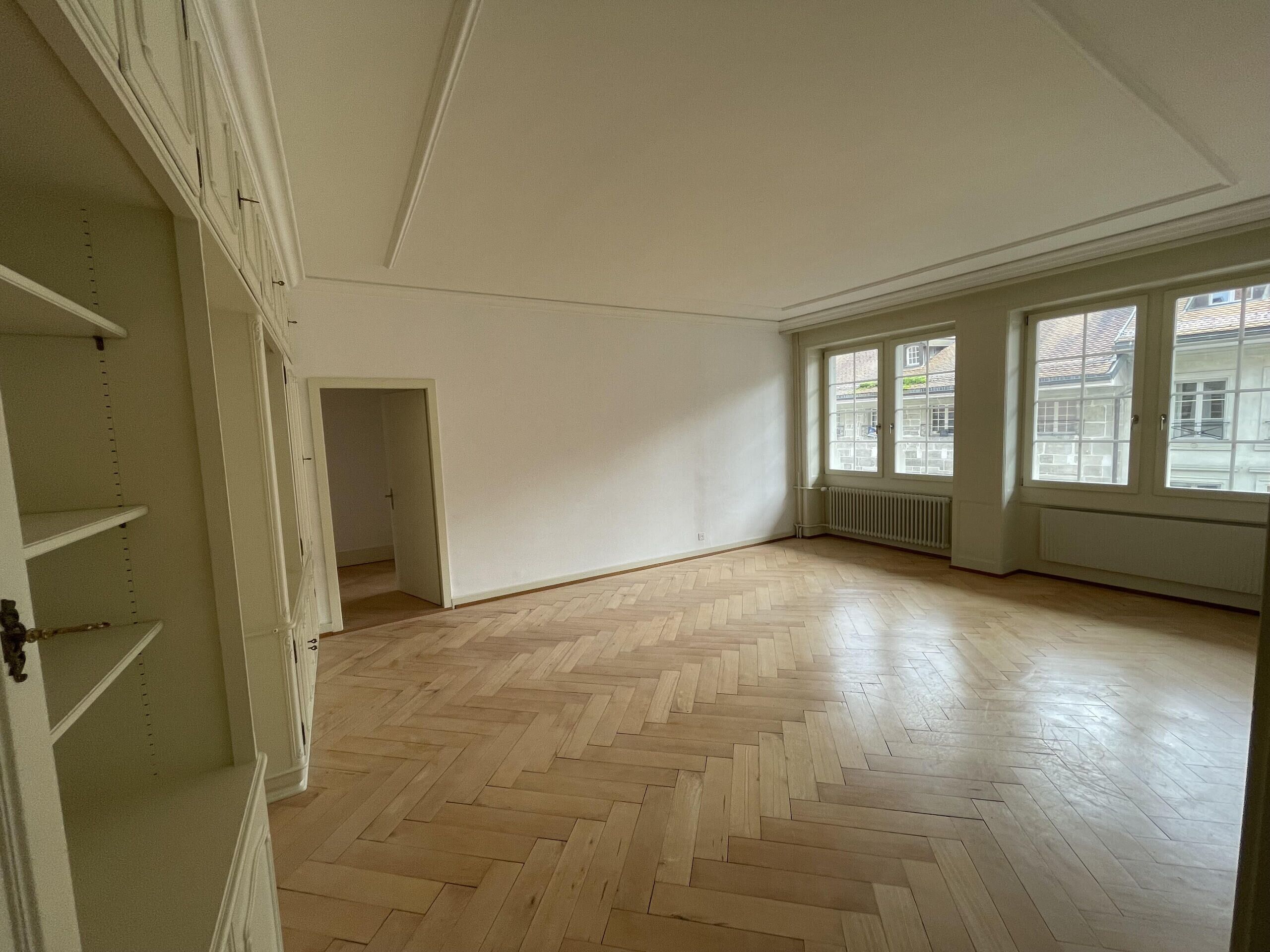 Heller leerer Altbau-Raum mit Fischgrätparkett
