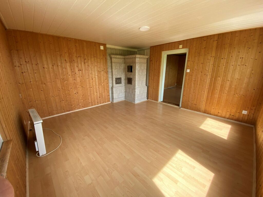 Leerer, holzvertäfelter Wohnraum mit Kachelofen