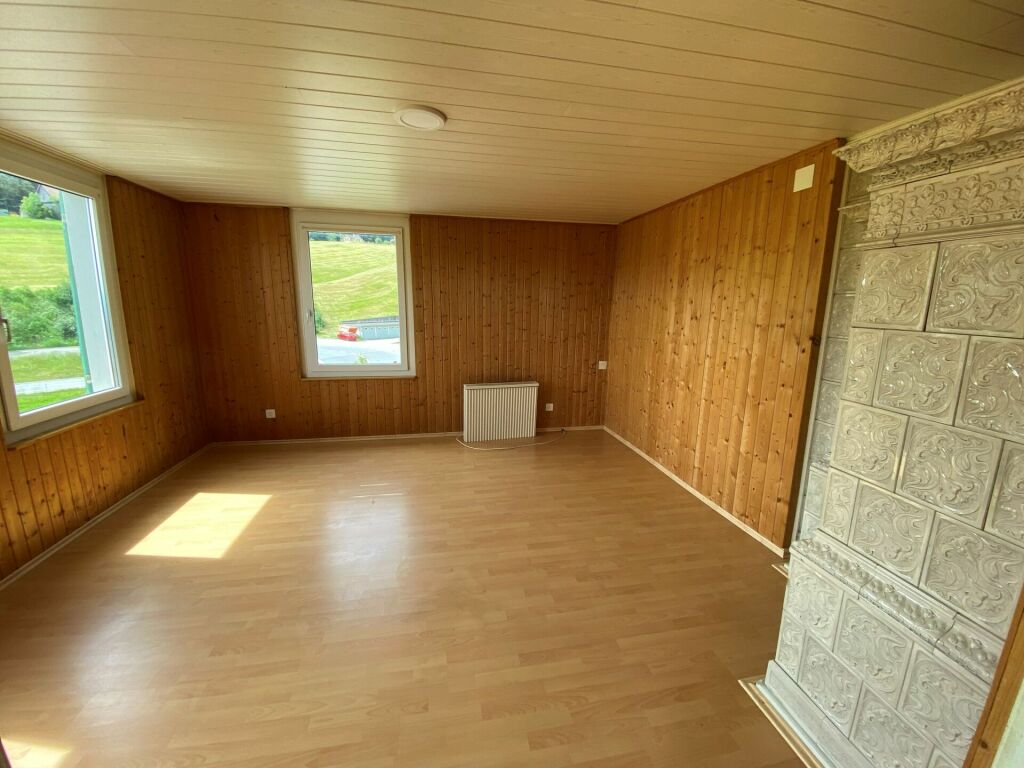 Heller, leerer Raum mit Holzvertäfelung und Kachelofen
