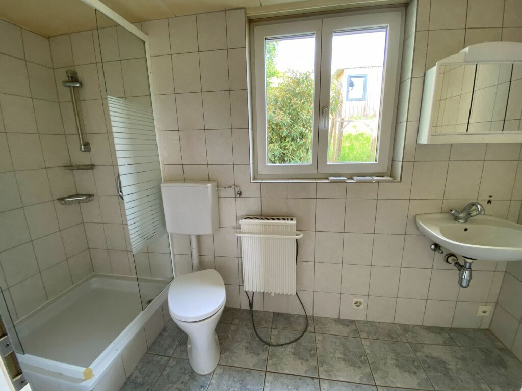 Badezimmer mit Dusche, WC, Waschbecken und Fenster