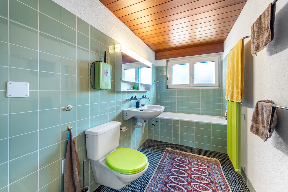 Badezimmer mit grünem WC-Sitz und Holzdecke
