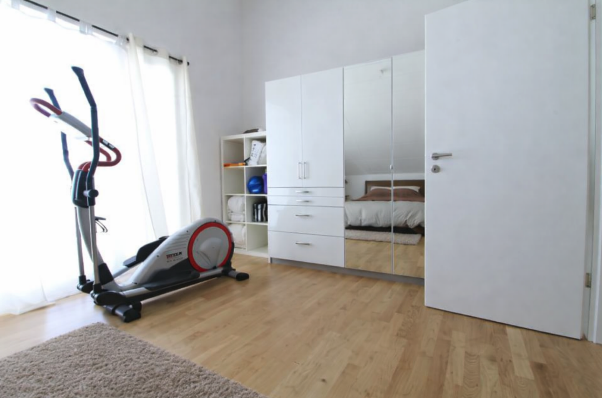 Helles Schlafzimmer mit Trainingsgerät und Kleiderschrank