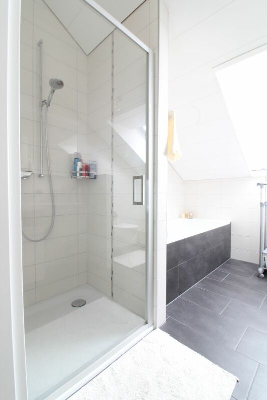 Modernes Badezimmer mit Dusche und Badewanne unter der Dachschräge