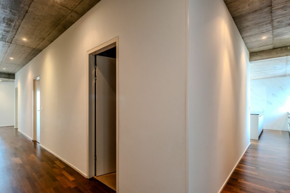 Moderner Flur mit Sichtbetondecke und Holzfußboden