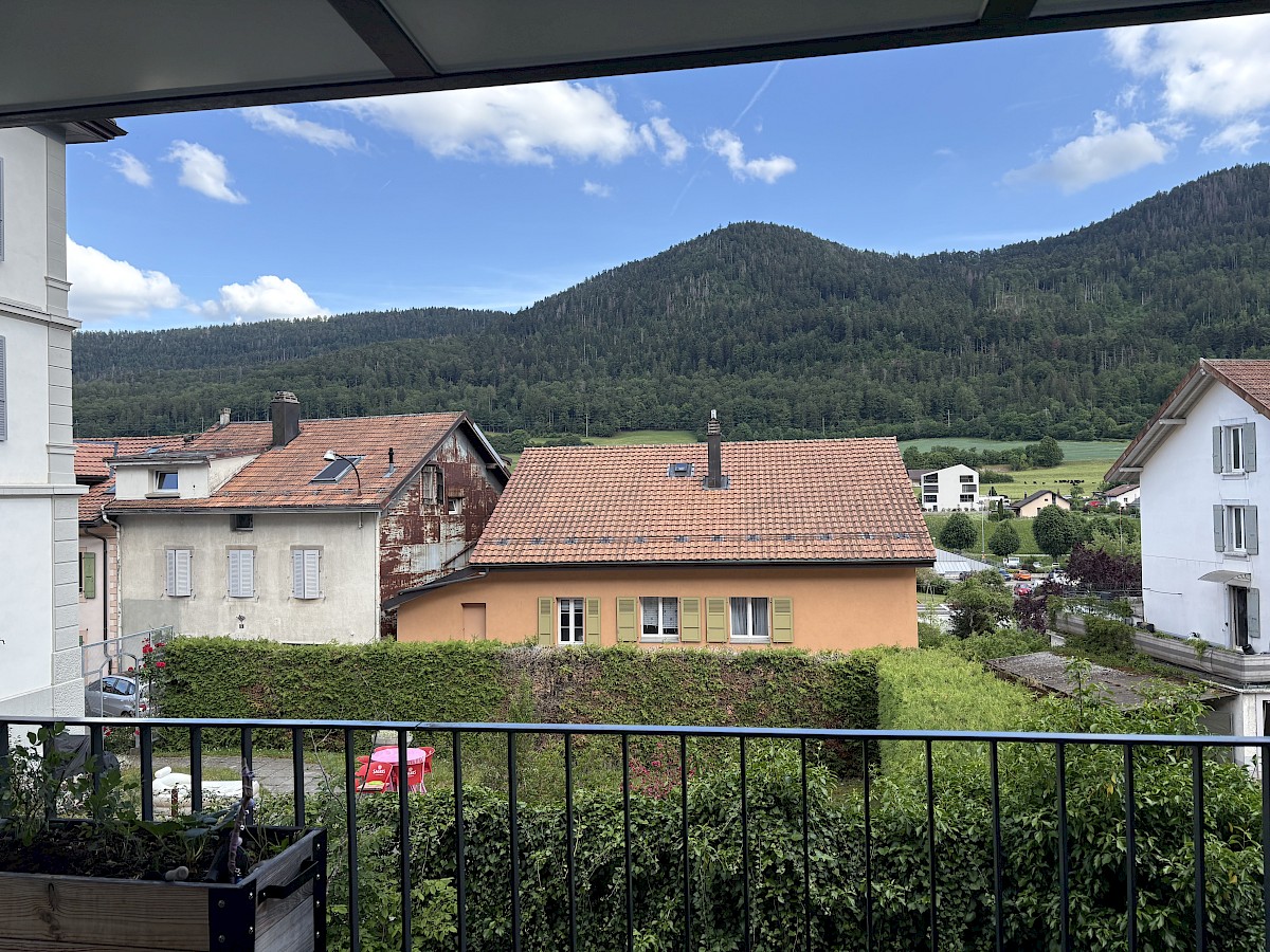 Balkonblick auf Wohnhäuser und Berglandschaft