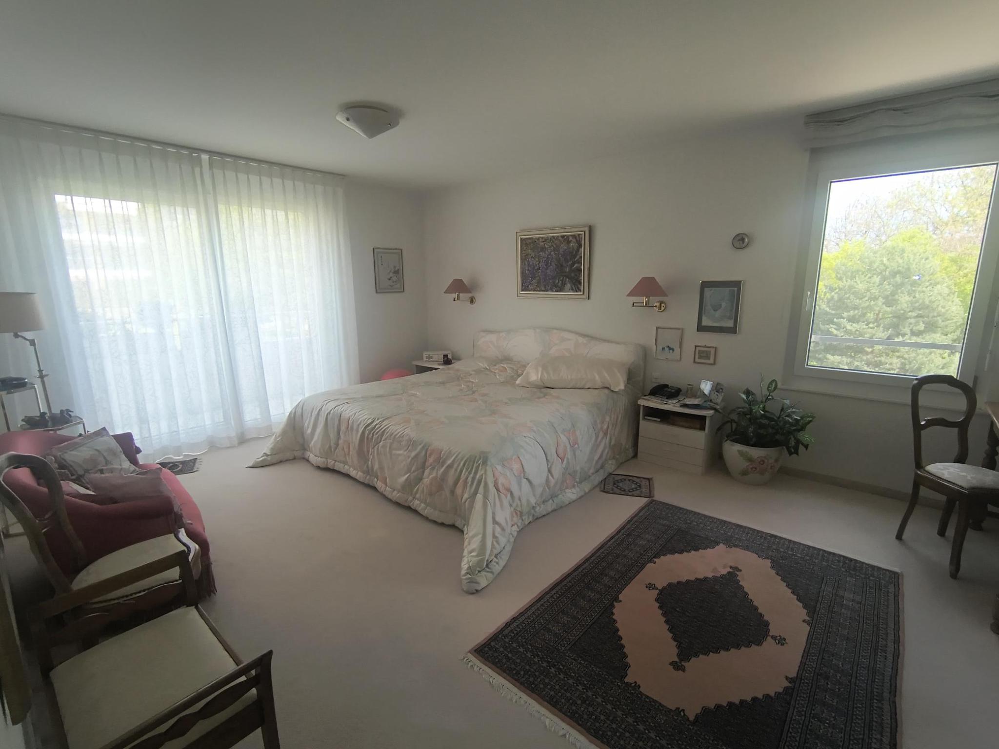Helles Schlafzimmer mit großen Fenstern und klassischer Einrichtung