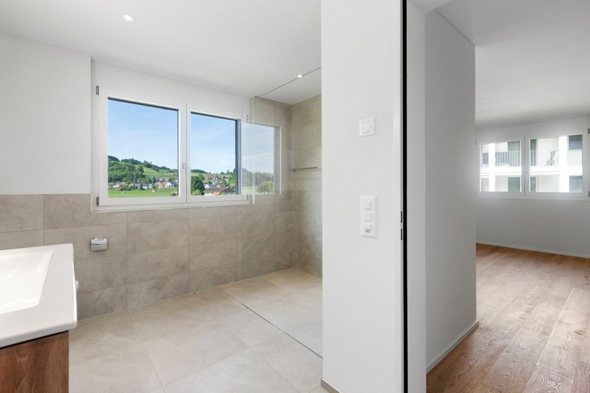 Modernes Bad mit Blick ins Grüne und angrenzendem Schlafzimmer