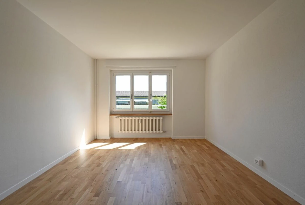 Leerer heller Wohnraum mit Fenster und Heizkörper